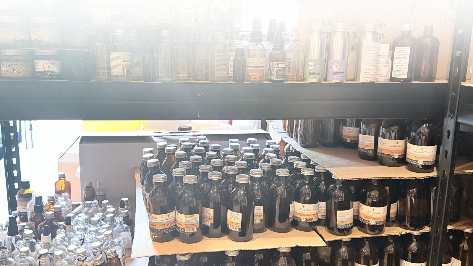 Returned Valley Mist glass bottles and jars stacked on shelves, awaiting label removal and cleaning as part of our National Glass Return System