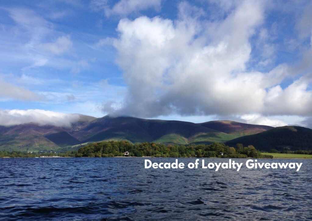 Lake and rolling hills under a blue sky in the Lake District National Park